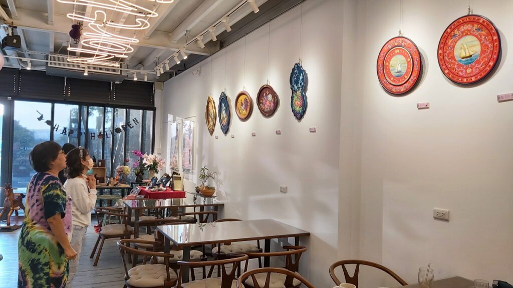 藝術家李芸溱為前來喝咖啡的客人解說她的作品。（圖/陳惠玲攝影）