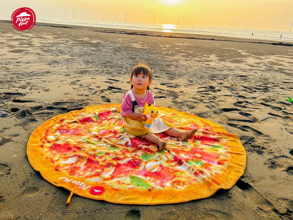 圖一：必勝客「比薩造型浴巾」將經典的「超級總匯大比薩」足足放大18倍，夏天戶外戲水或窩在家都派得上用場！