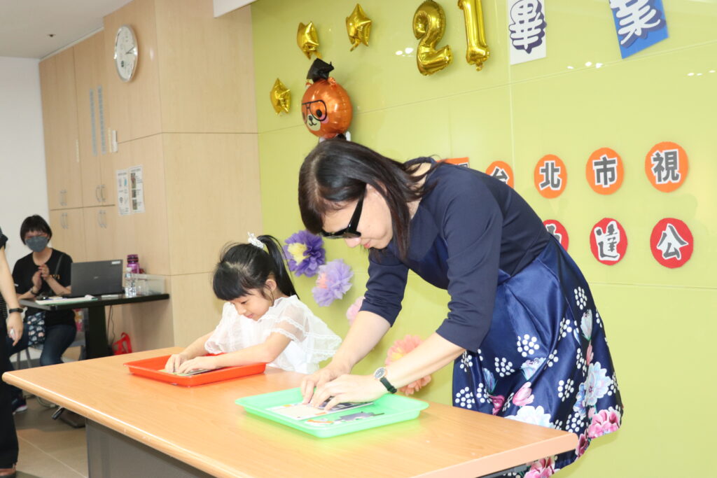 圖說：台北市教育局特教科科長官月蘭發（右）挑戰和畢業生代表比賽拼圖。