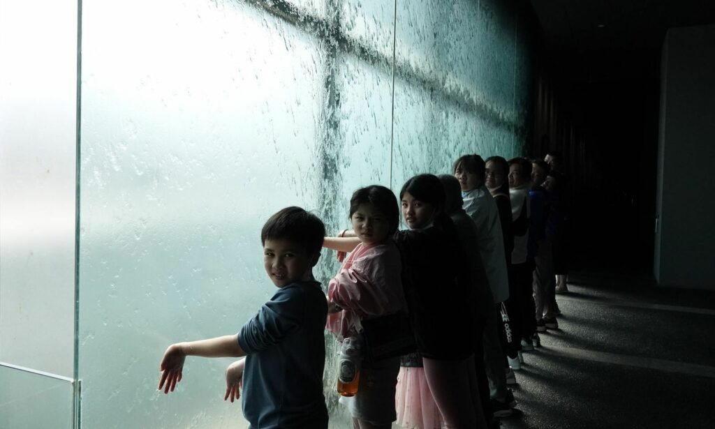 在世界宗教博物館水幕牆前，體驗以水潔淨心靈的感受。（圖由世界宗教博物館提供）