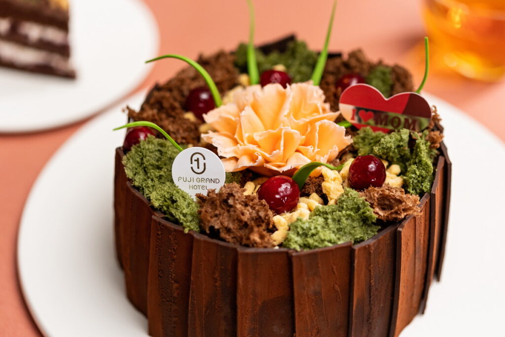 富士大飯店今年以pantone流行色-溫柔桃為發想，選用法國莊園頂級巧克力、酒漬櫻桃設計出「好馨情」母親節蛋糕。