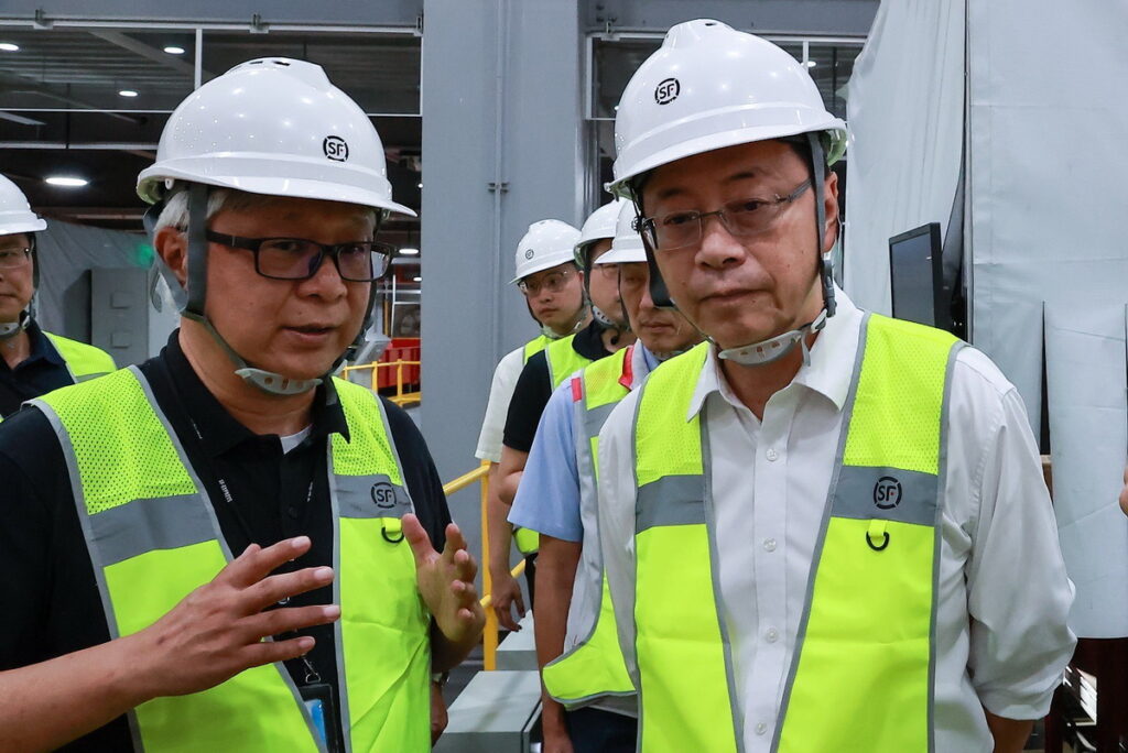台灣順豐總經理潘逸俊向桃園市長張善政說明全自動化分揀設備運作模式,大幅提升貨件轉運效率。