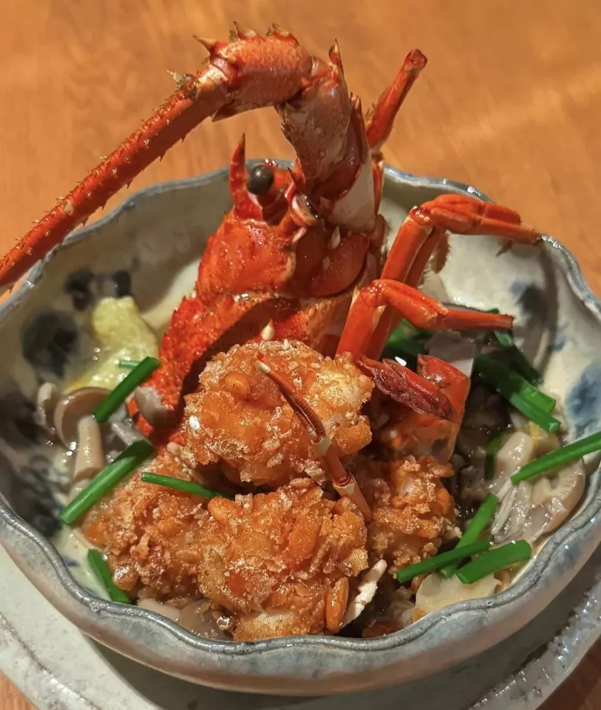 台北美福大飯店晴山日本料理於8/18 起推出的「食之都美食大使 匠心旬味」晚間套餐，主菜「伊勢龍蝦米菓揚、炭烤茄子、蓮藕、百菇韭菜花芡」，鮮嫩蝦肉與酒蒸龍蝦殼，雙重香氣融和，鮮味滿溢。圖/台北美福大飯店