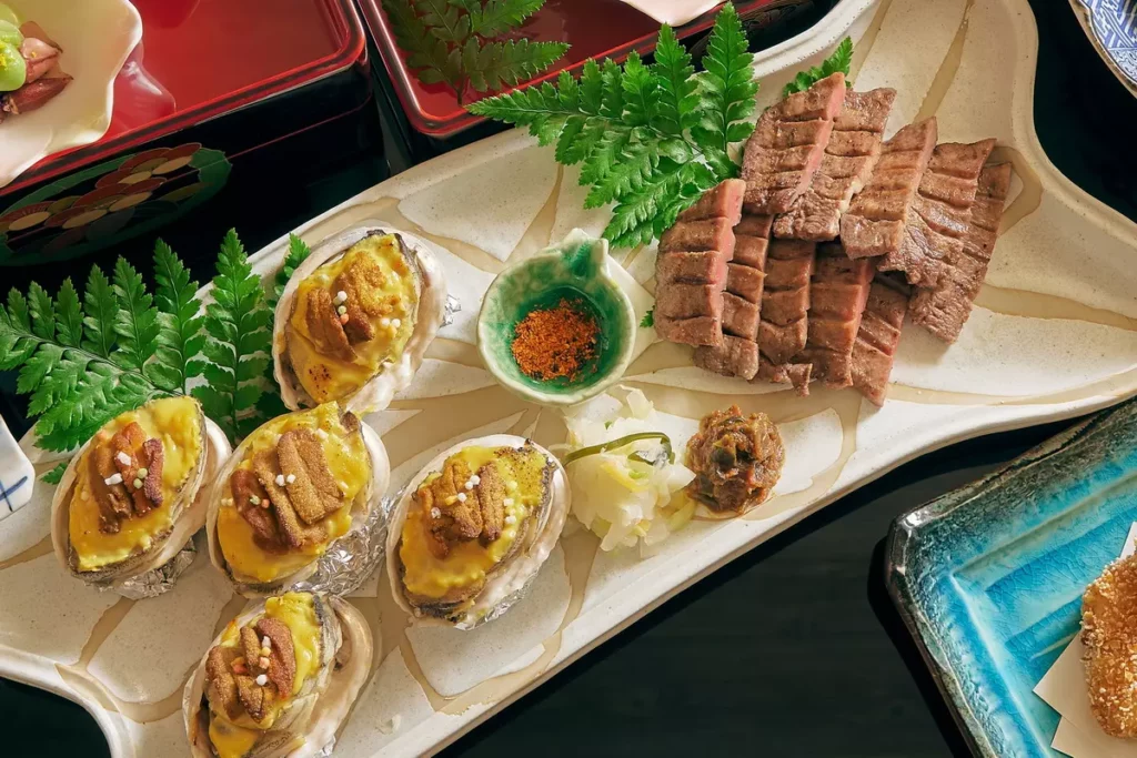 「和饗大皿盛－賞櫻之宴」主菜為燒物、煮物、油物三選二，燒物為HAYASE招牌厚切烤牛舌與炙燒鮑魚海膽。(圖/ JR東日本大飯店台北)