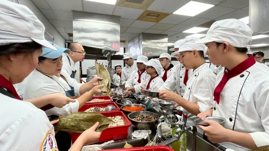 手把手傳授臺味技藝!吳鳳科大餐管系老師親自帶領外籍學生,從摺粽葉到紮粽繩,細心體驗包粽樂趣。